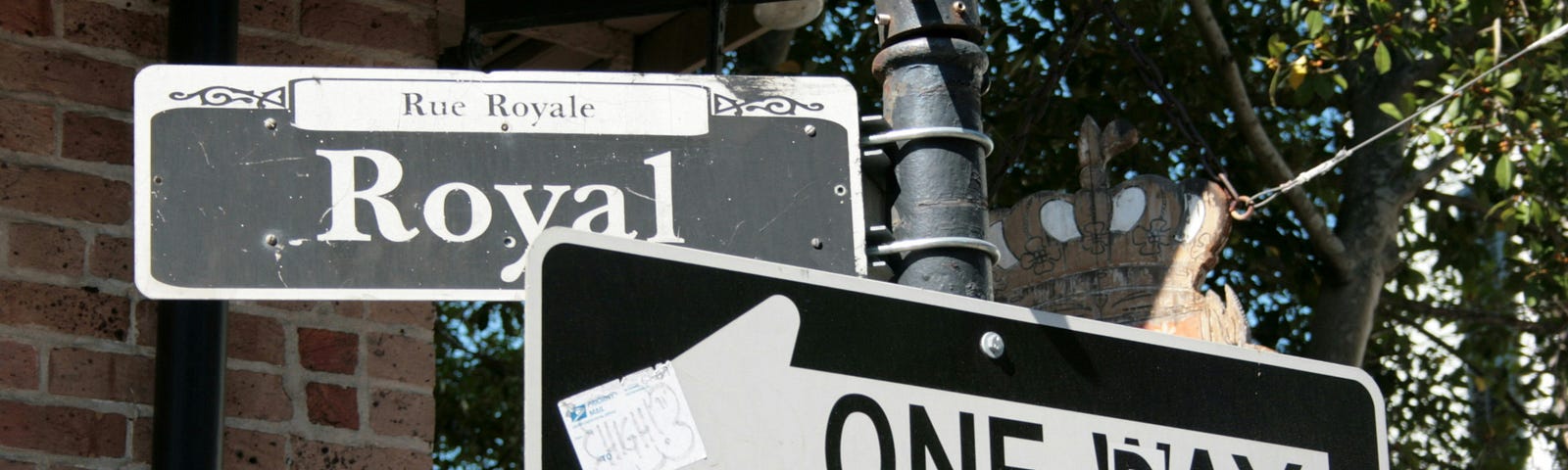 Two street signs are shown. The focus is on a “one way” sign with an arrow, but a sticker was used to cover over the “w” to make it appear as if the sign says “one day.”