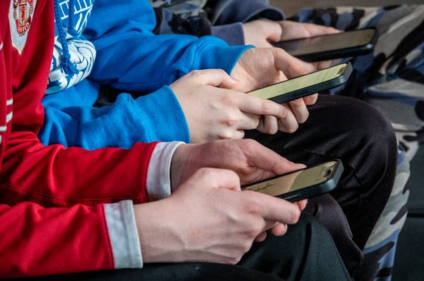 Close-up of thee people holding cell phones.