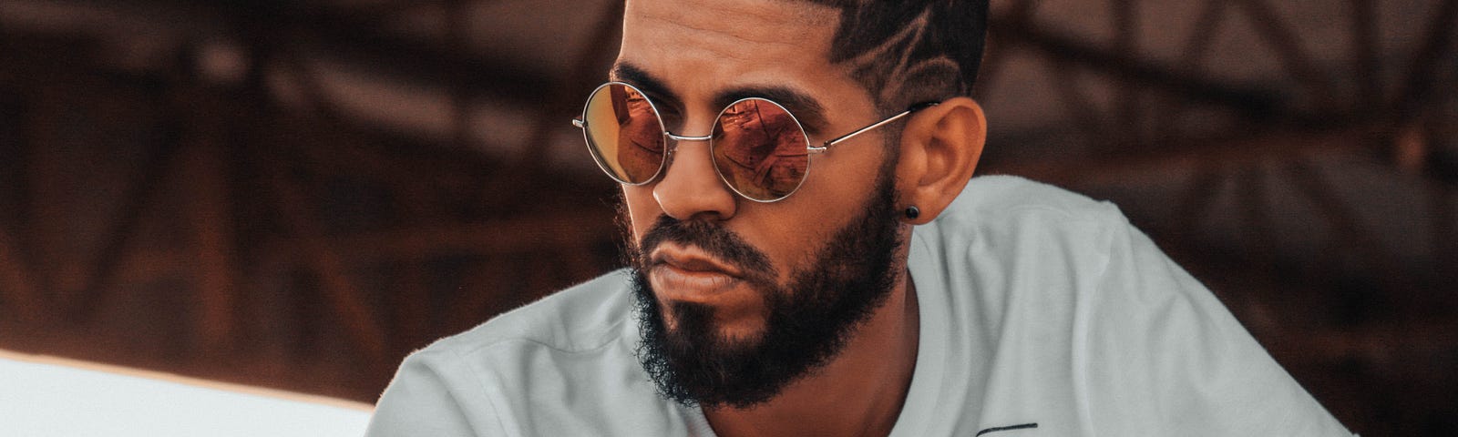 Still of a man with a beard, fancy hairdo, and stylish shades