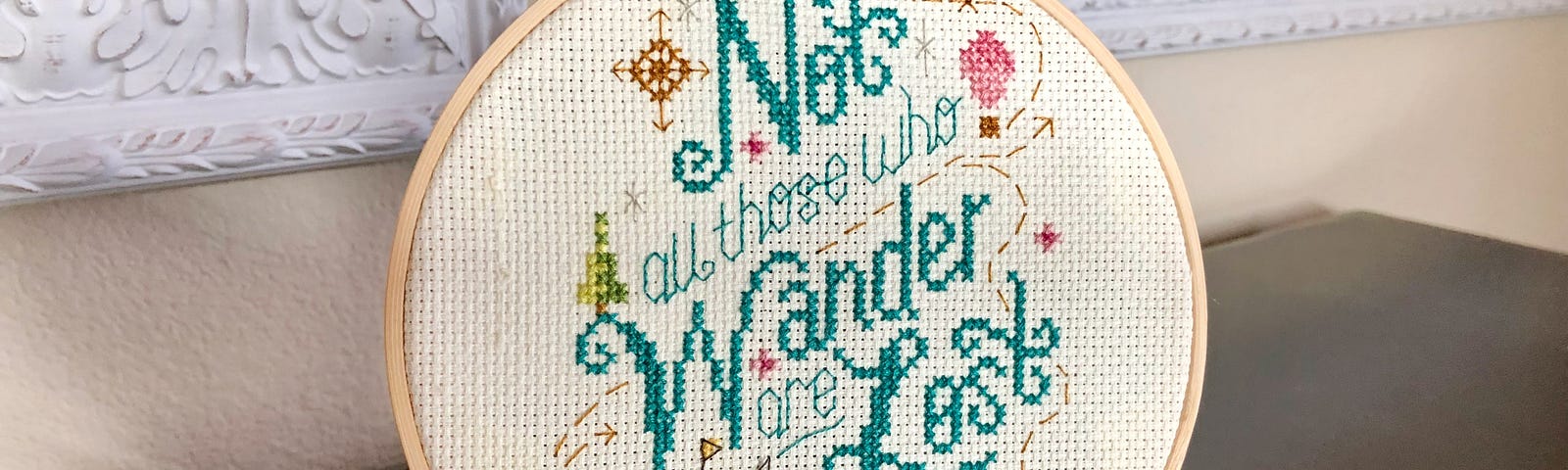 A cross stitch in a round frame saying ‘not all who wander are lost’