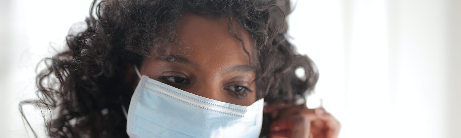 A black woman putting on a face mask