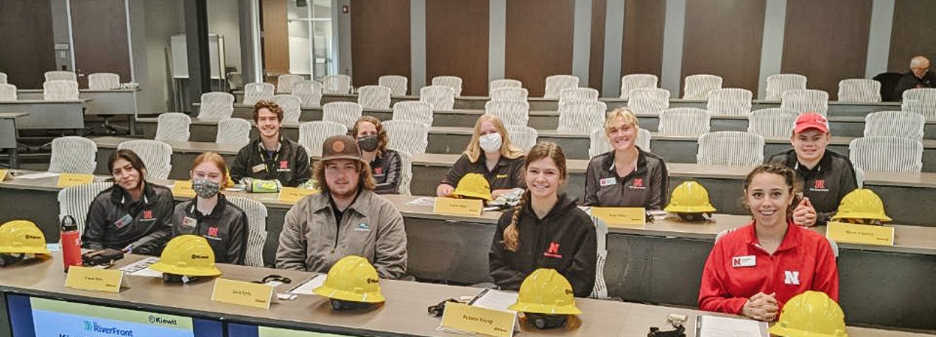 Kiewit Scholars sit at tables with hard hats before a tour