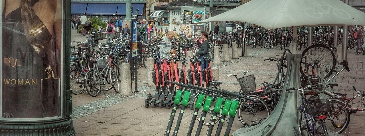 IMAGE: An urban square filled with parked bicycles and electric scooters