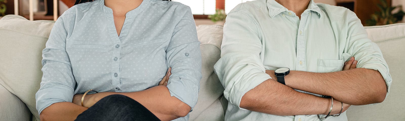 A couple that are seated with arms crossed and looking away from each other