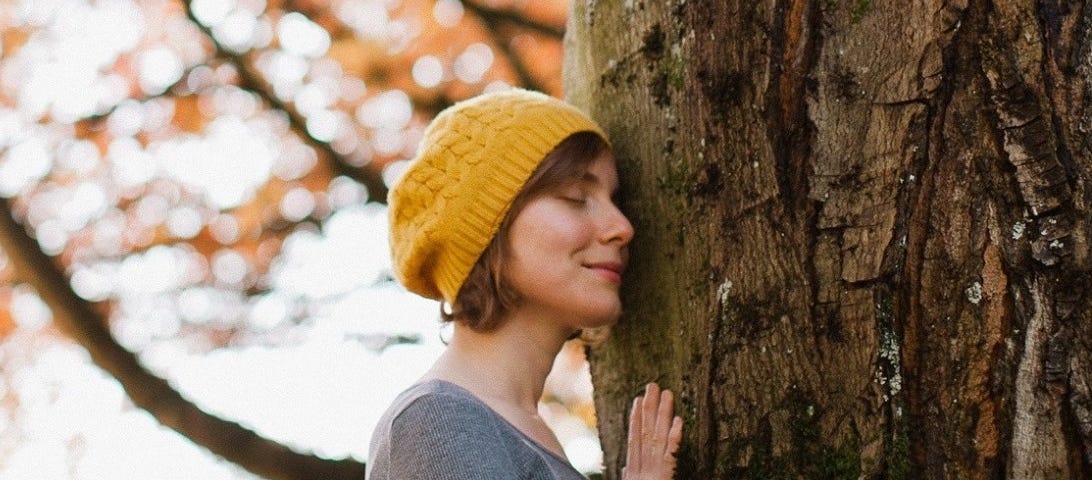 Woman gently sensing and caressing a tree with her eyes closed.