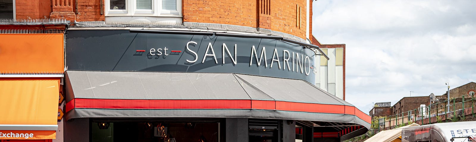 A café with outdoor seating on the corner of two streets.