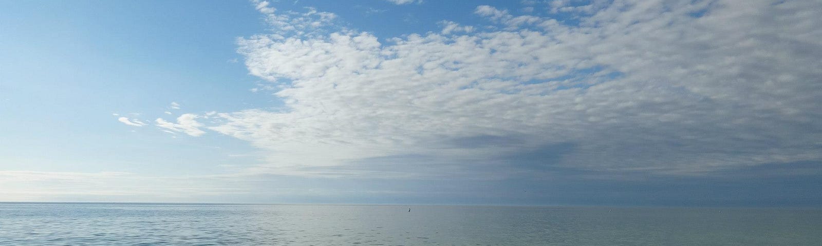Calm ocean with blue sky and fluffy clouds