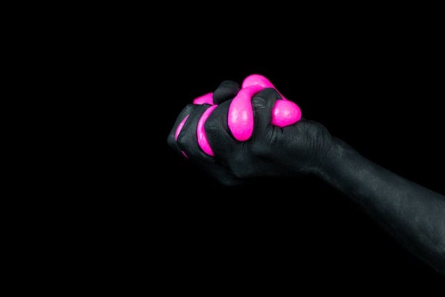 a hand painted black squeezing bright pink slime between its fingers.