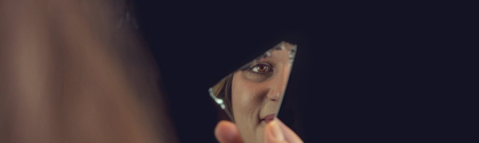 Person Holding a Piece of Broken Mirror with Reflection