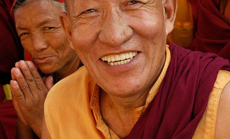 Happy Tibetan monk holding a red blindfold in a ritual in Nepal