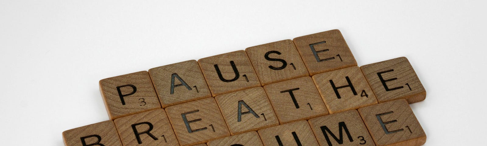 Scrabble tiles spelling out “Pause, Breathe, Resume”