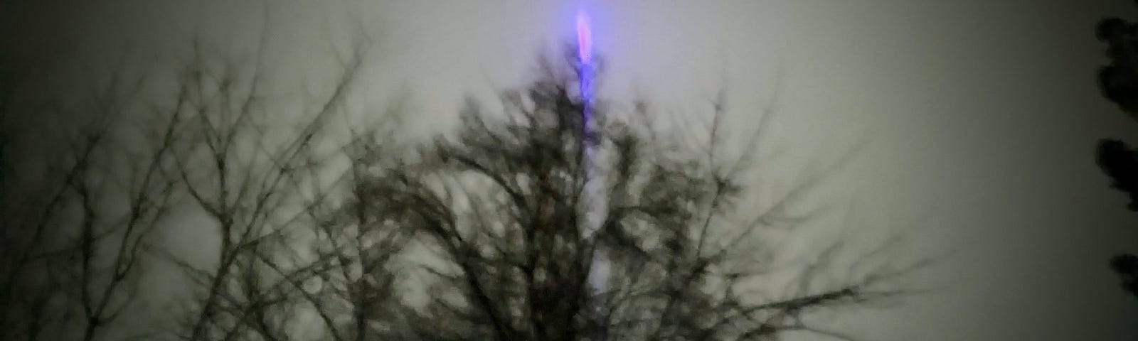 Photograph of a gray sky with a purple shaft of light.