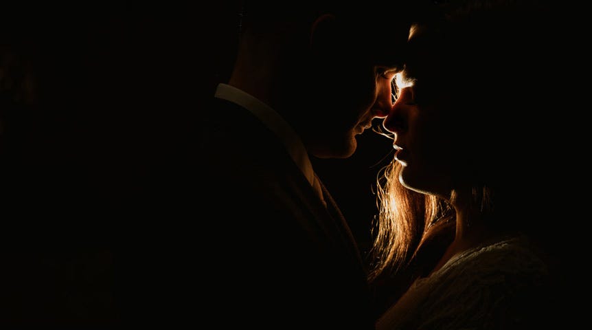 Silhouette of man and woman close to kissing in low light