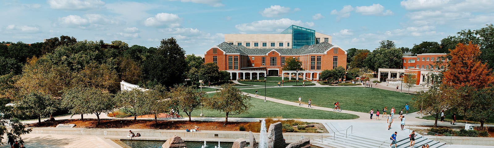 Students cross campus in front of Broyhill Fountain with the Raikes School and the College of Business in the background