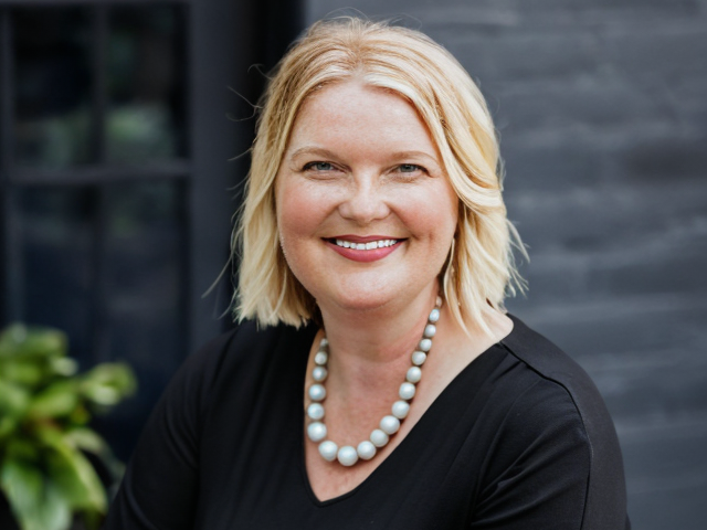 Amy Leneker photo wearing a black blouse and white necklace.