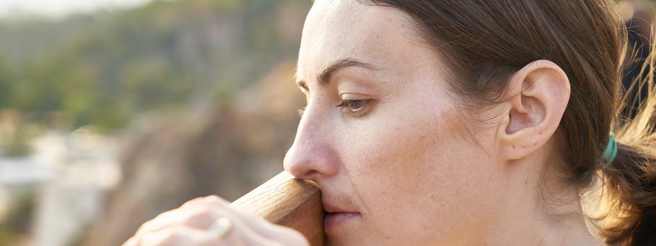 Woman looking over a rail pensively into the distance.