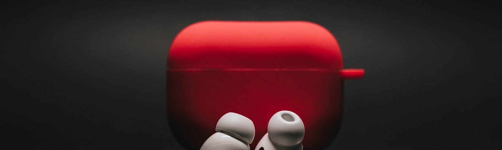 Earbuds red case with earbuds in front of the case in a black background.