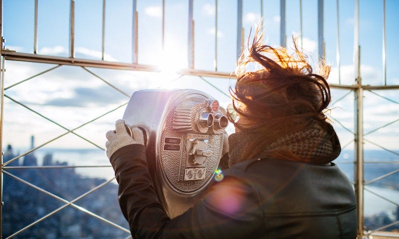 Woman using coin binoculars at the Empire State Building in New York City.