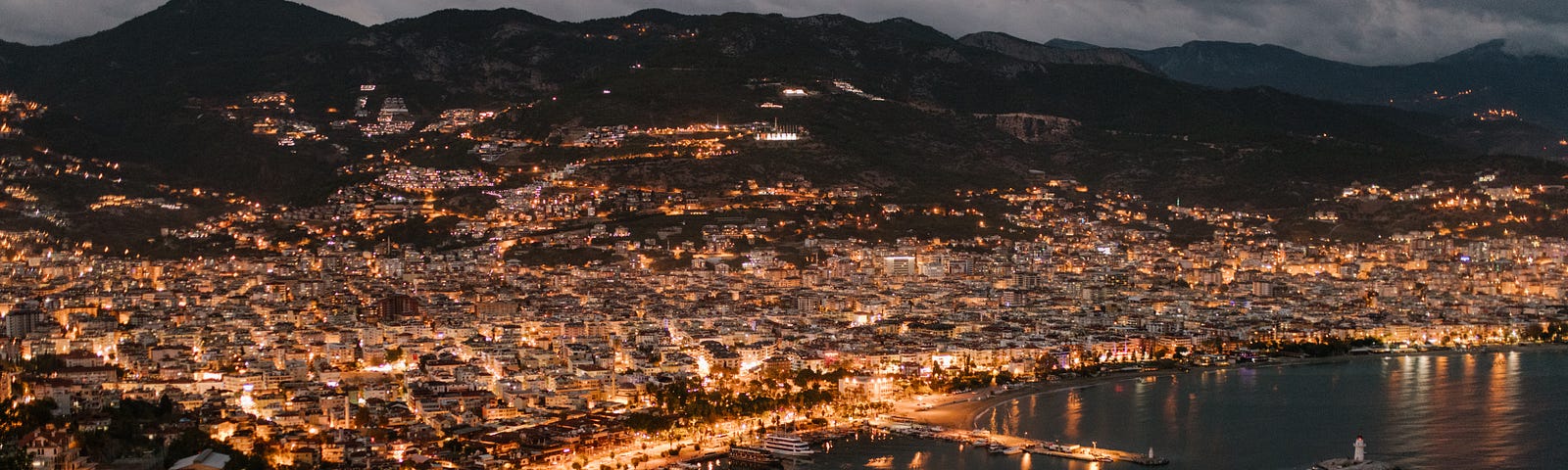 A picturesque image of a coastal town at night with lights shining.
