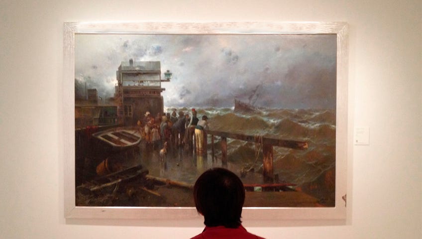 Woman looking at a large seascape painting.