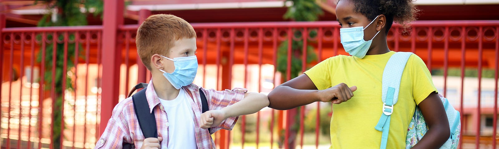 A boy and girl in masks ‘elbow bump’ at school