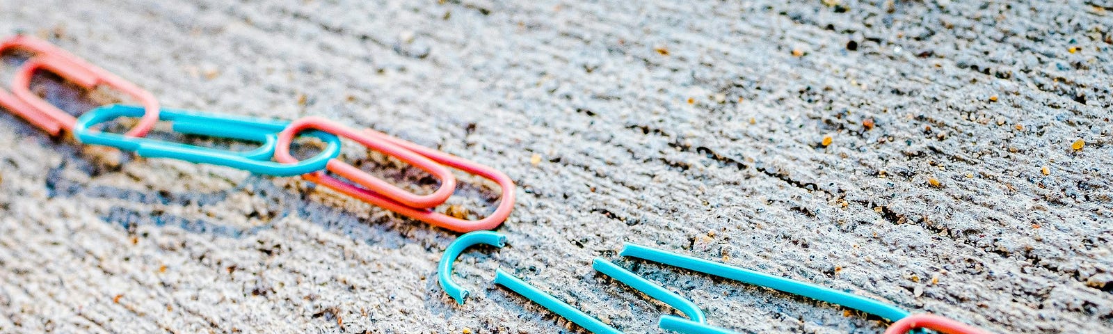 A connected chain of red and blue paper clips with one broken blue clip in the middle, which breaks the chain.