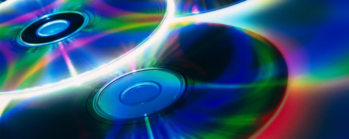CDs at an oblique angle, with multi-coloured light shining off their reflective surfaces.