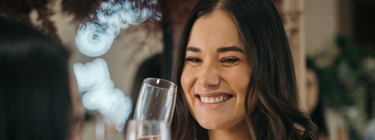 A woman smiling and holding a glass of champagne.