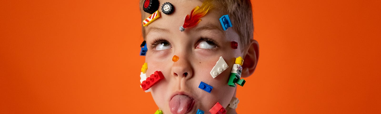 A boy sticking his tongue out with toys on his face