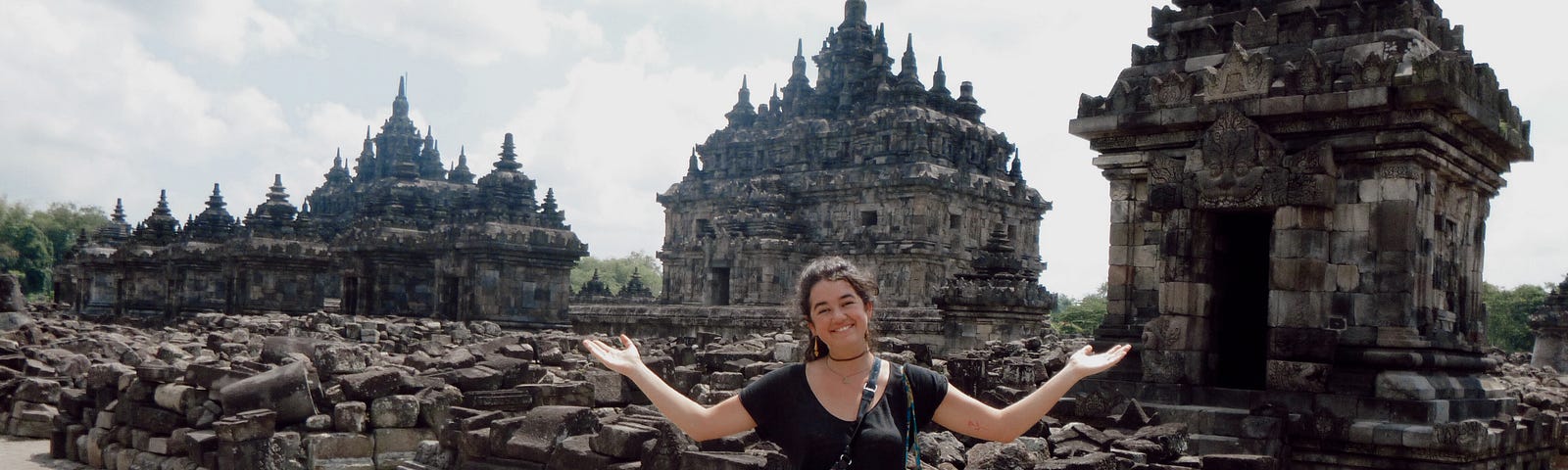 a woman (me) smiling and making the “I don’t know” gesture in front of a temple in Java, Indonesia
