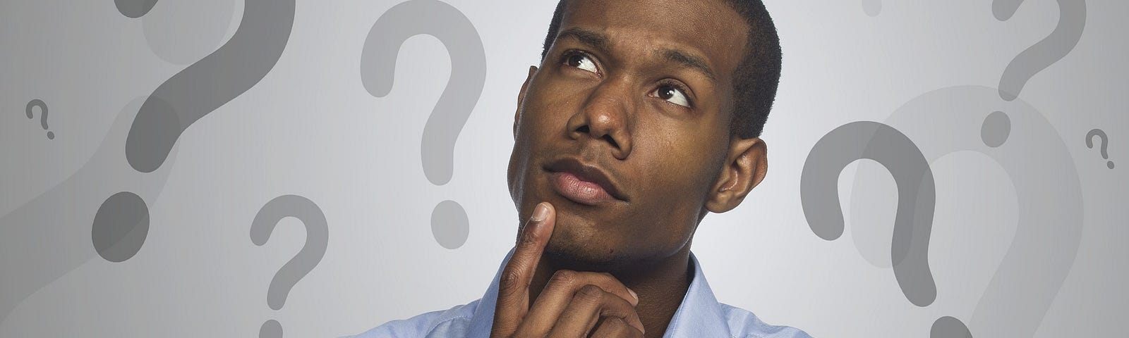 Man Of African Descent With Hand On Chin And Pondering With Question Marks In The Background