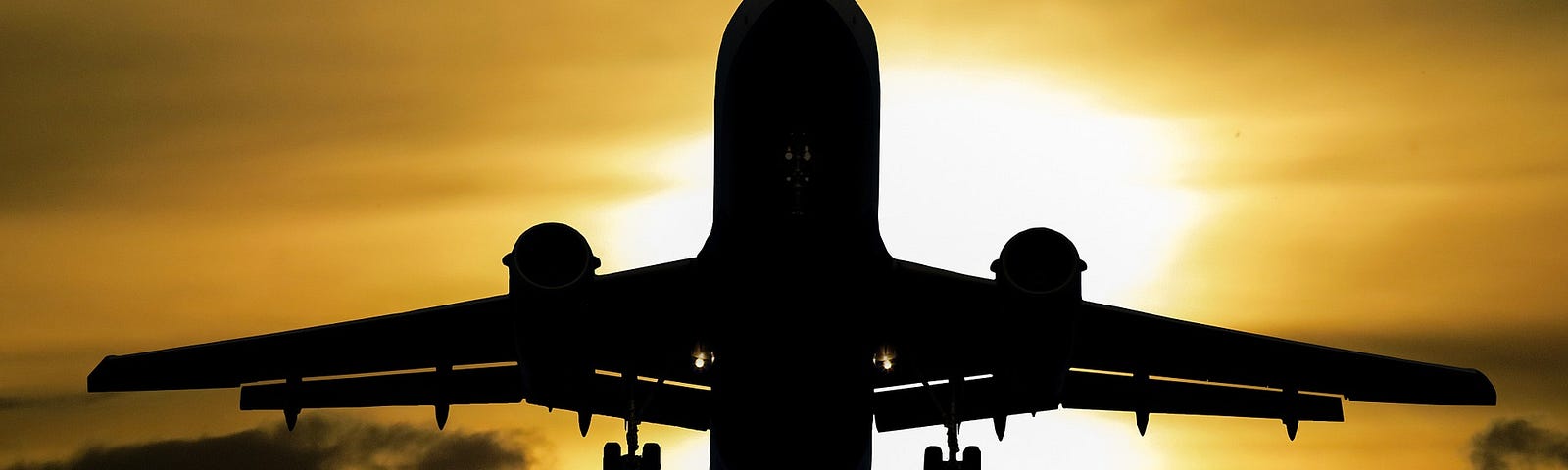airplane silhouette with the sun and clouds in background