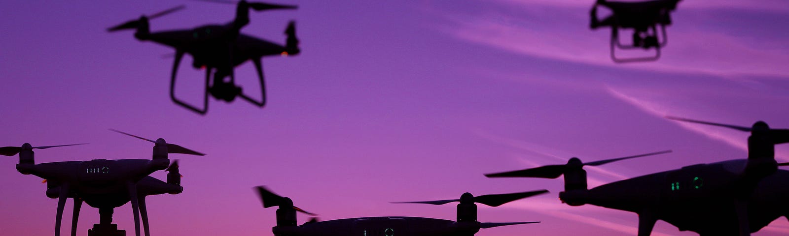 Five drone silhouettes in the sky at sunset