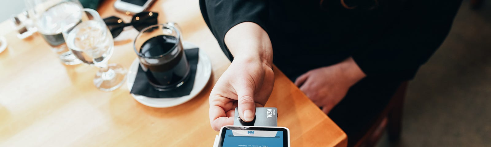 Customer using mobile payment tech in a coffee shop.