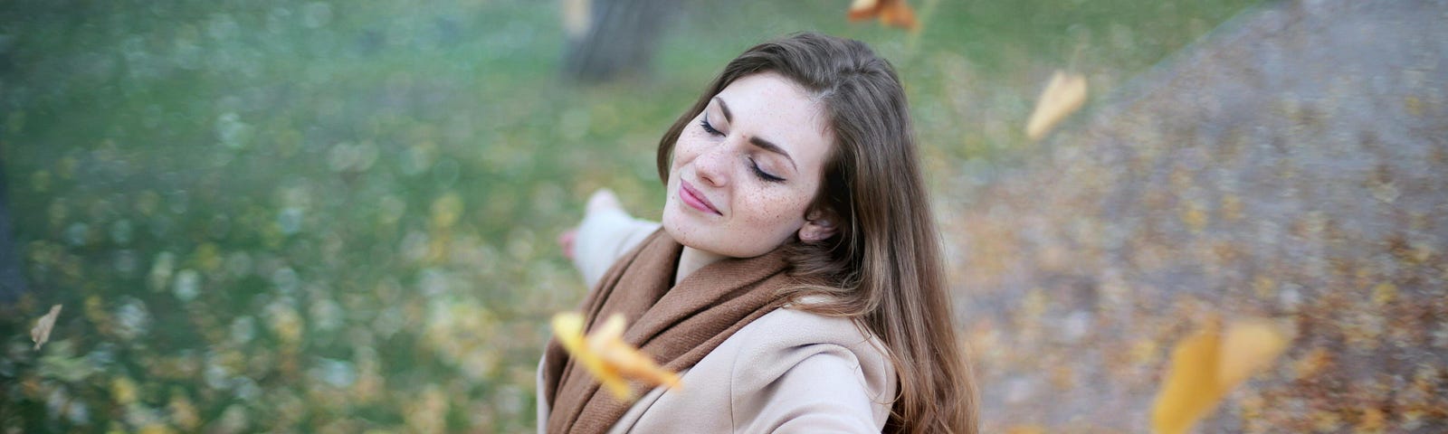 Woman Open Arms While Closed-eyes Smiling in the park on a fall day.