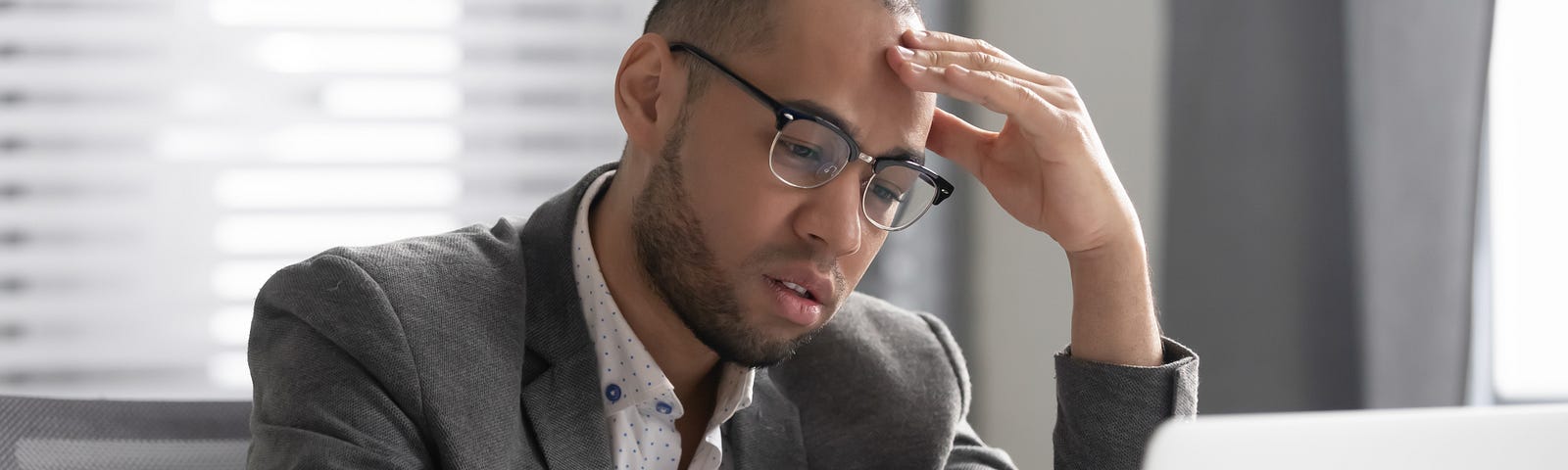 Man sitting at laptop computer with look of dread.