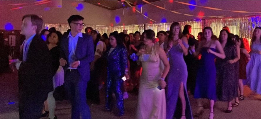 Photo of people dancing at Poet Prom, bathed in red, blue and purple light.