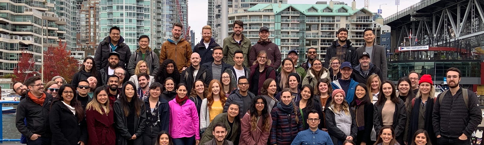 Team Thinkific poses on a dock at Vancouver’s Granville Island on a cloudy day during a quarterly team wide celebration.