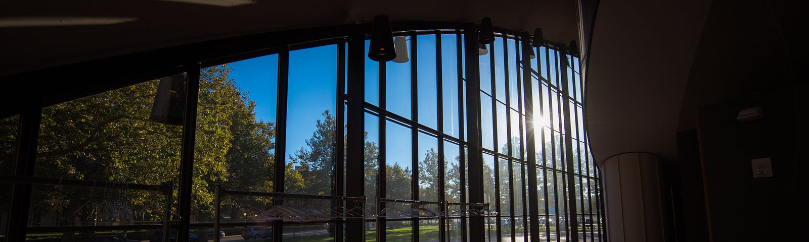 View from inside the Kresge auditorium of the sun shining and casting shadows on the ground in the foyer