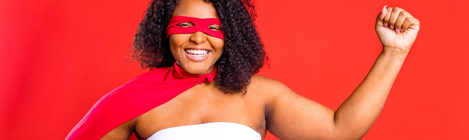 latin hispanic woman in red eye mask and long superhero cloak in studio background