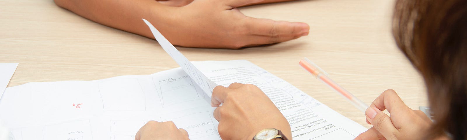 Hands on a desk with papers in a mock interview session