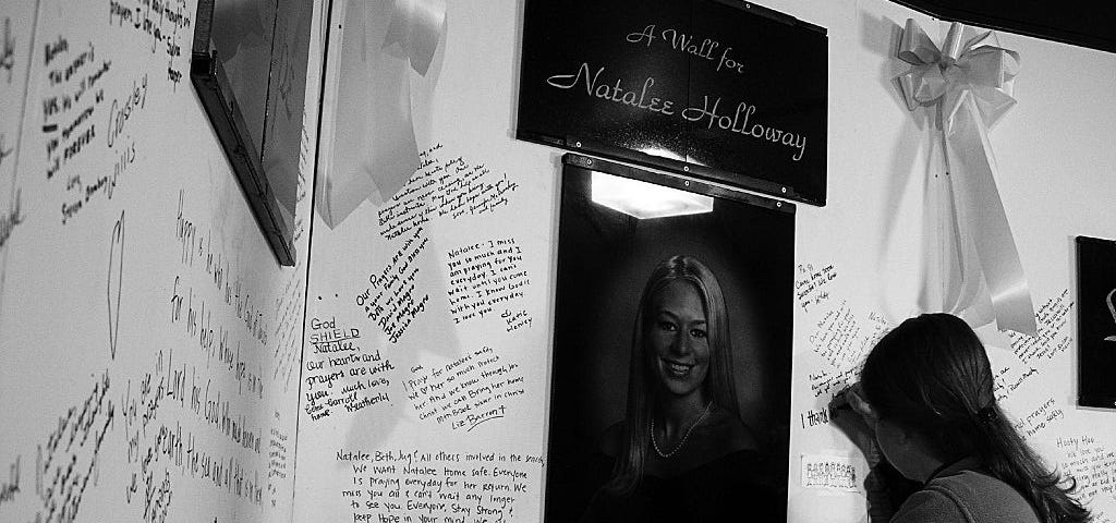 A woman signing a memorial wall dedicated to missing woman, Natalee Holloway.