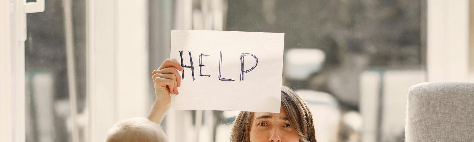 Stressed out single parent holding a sign asking for help.