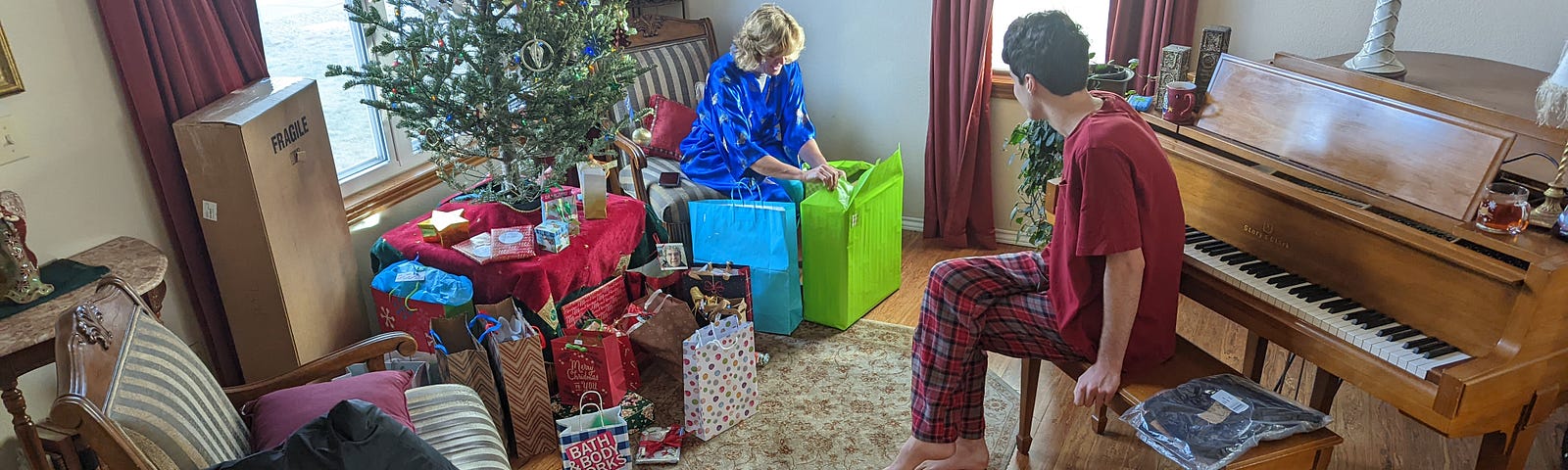 Three people sit around a living room opening presents.