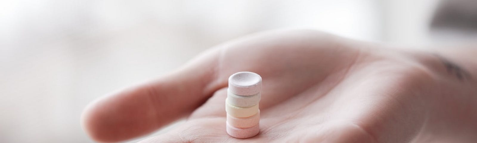 A hand holding a stack of pills.