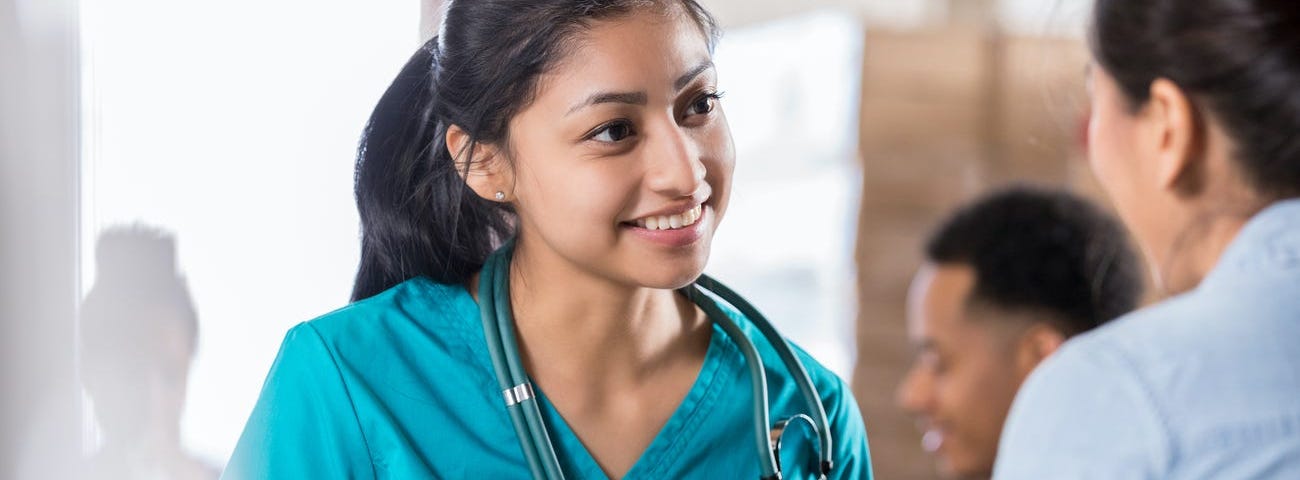 A nurse talking to someone while holding a pen.