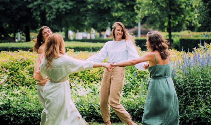 Four women in a circle dancing outside.