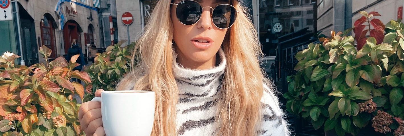 a woman sipping coffee in switzerland wearing animal print dress