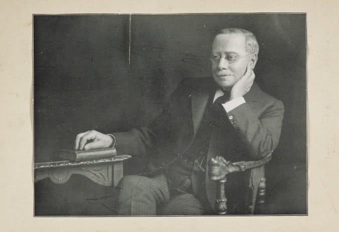 black and white photograph of a seated man in his study