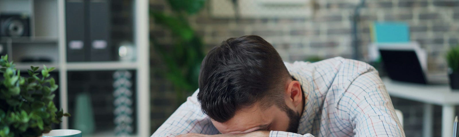 a man seating and sleeping on his desk